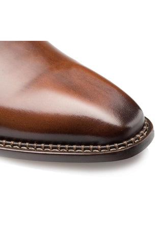 Close-up of a cognac calfskin leather whole-cut Oxford shoe featuring a smooth plain toe and detailed contrast stitching.